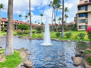 A hotel with a central water feature surrounded by palm trees and a well-maintained lawn. - Kamaole Sands across from beach/entertainment (Kihei)