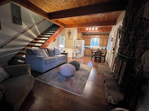 Ein gemütliches Wohnzimmer mit einer Couch, Hocker und einer Treppe, die zur Küche führt.
