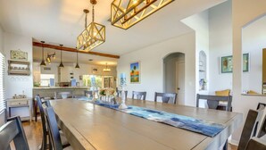A spacious dining area with a long wooden table, modern pendant lights, and a view into the kitchen. - Resort Style Tranquil Oasis in Beautiful Port Saint Lucie , Florida (Port St. Lucie)