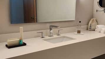 Une salle de bain moderne avec un grand miroir, deux lavabos et un porte-serviettes.