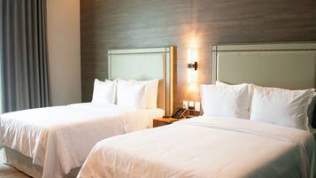 Une chambre d’hôtel avec deux lits, une tête de lit en bois, une table de chevet avec une lampe et un téléphone.