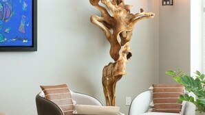 Un salón moderno con una escultura de madera original, dos sofás con cojines estampados y un cuadro abstracto enmarcado.