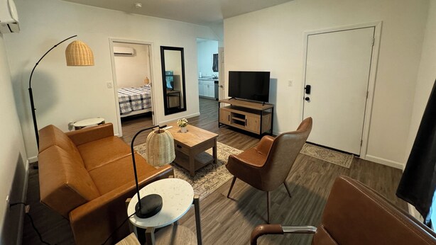 A modern living room with a sofa, armchair, coffee table, TV, and a dining area. - Central ICT.B (Wichita)