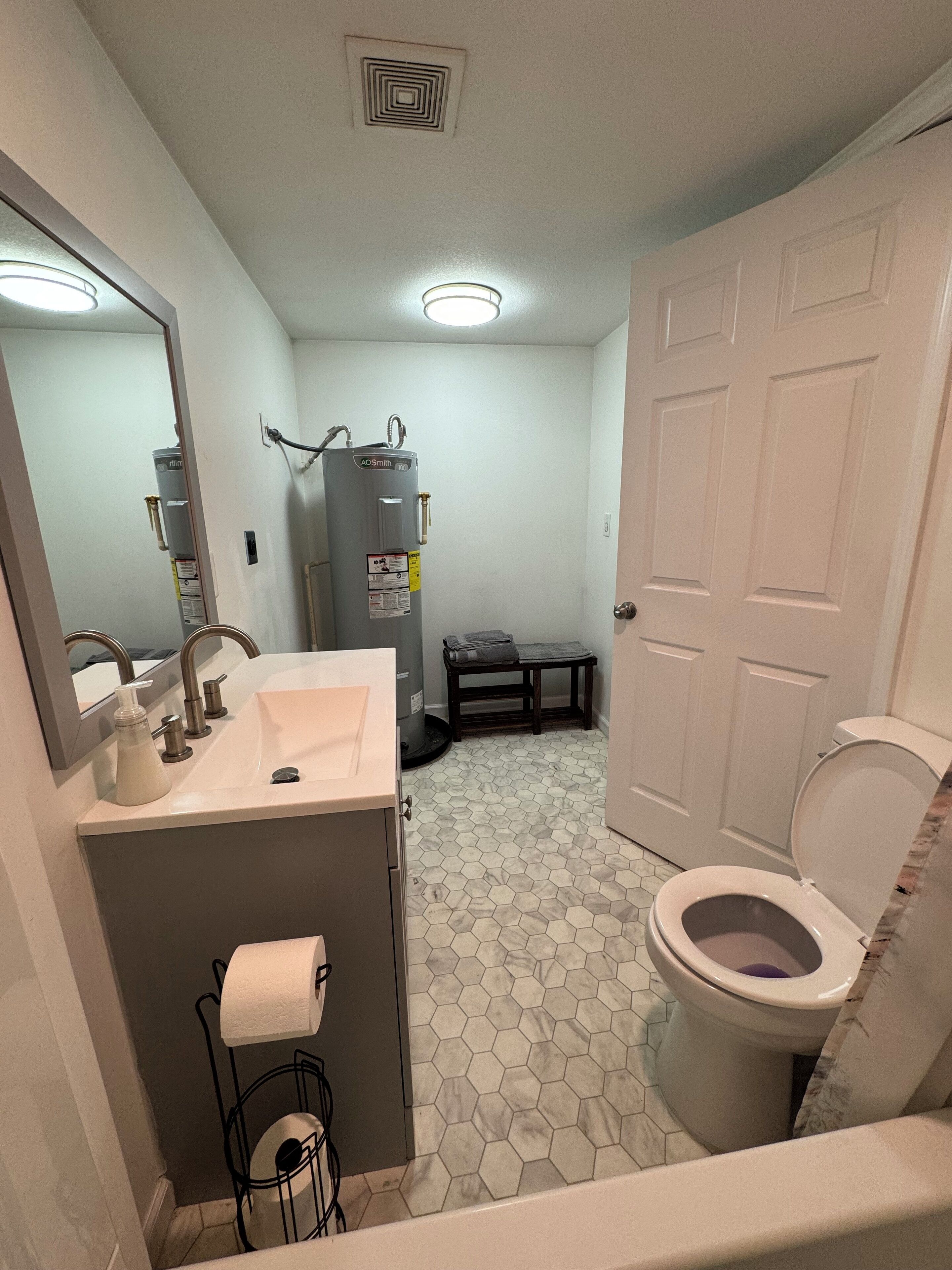 A bathroom with a sink, toilet, and a water heater.