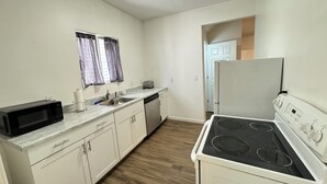 A compact kitchen with white cabinets, a microwave, a toaster, a sink, and a stove. - Central ICT.B (Wichita)