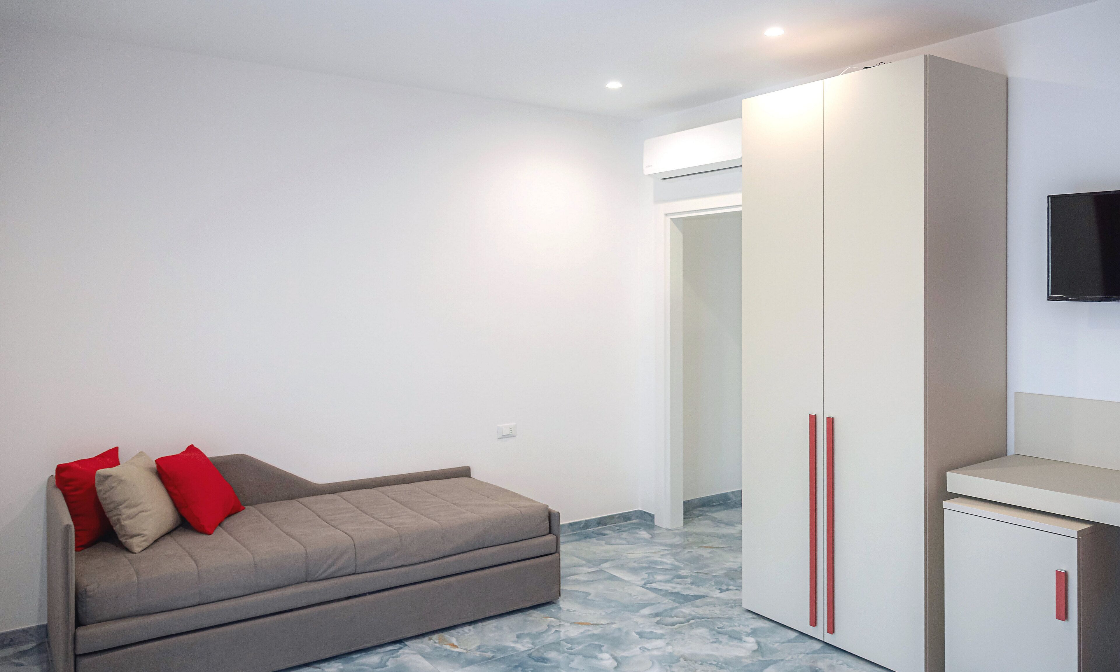Una habitación pequeña y moderna con un sofá, un armario y un televisor.