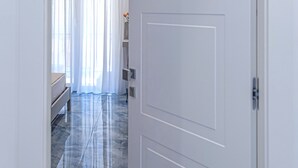 A hallway with a white door marked with the number 4, leading to a room with a bed and a window with sheer curtains. - Maison Matie B&B Ercolano (Ercolano)