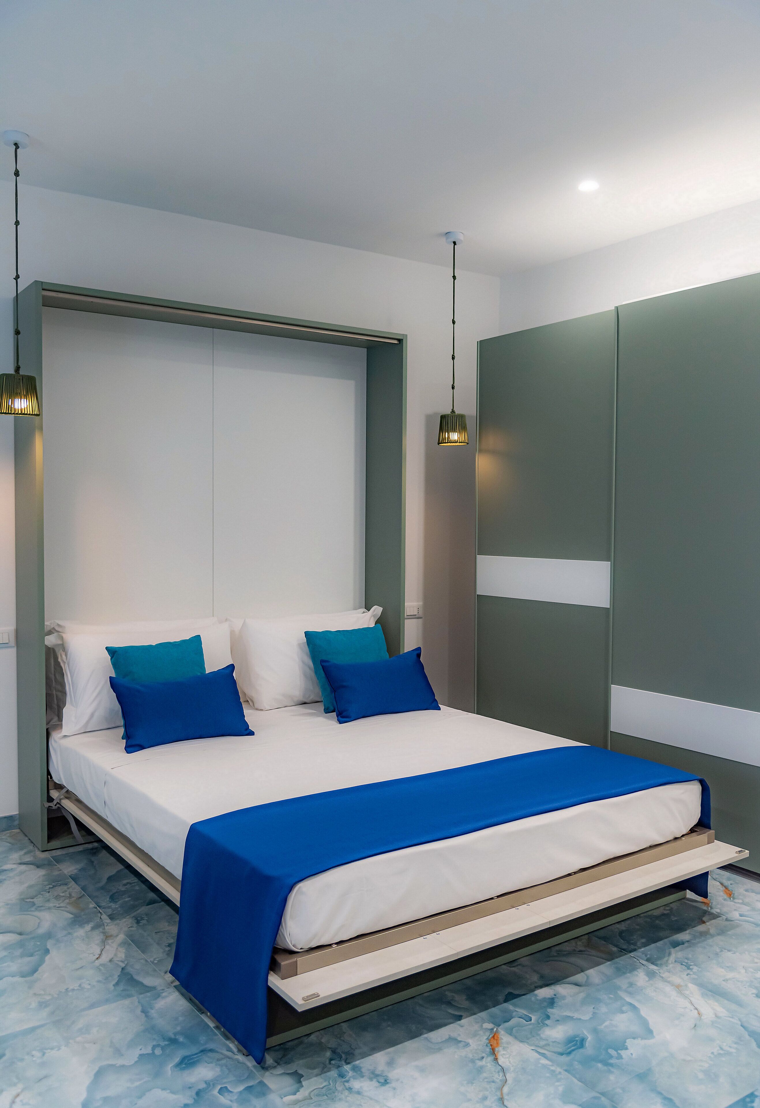 Un dormitorio moderno con una cama, dos almohadas, una colcha azul y un armario.