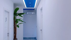 A modern hallway with a blue-lit ceiling, a potted plant, and a marble floor. - Maison Matie B&B Ercolano (Ercolano)