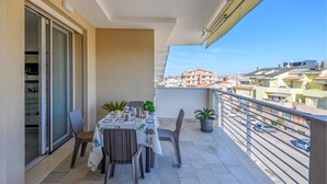 Ein Balkon mit Tisch für zwei Personen, Stühlen und Topfpflanzen.