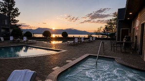 A pool area with lounge chairs, a hot tub, and a sunset view.
