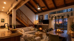 A spacious living area with a fireplace, a dining table, and a large window overlooking a scenic view.
