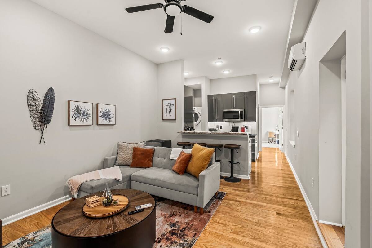 A modern living room with a grey sectional sofa, a wooden coffee table, and a ceiling fan.