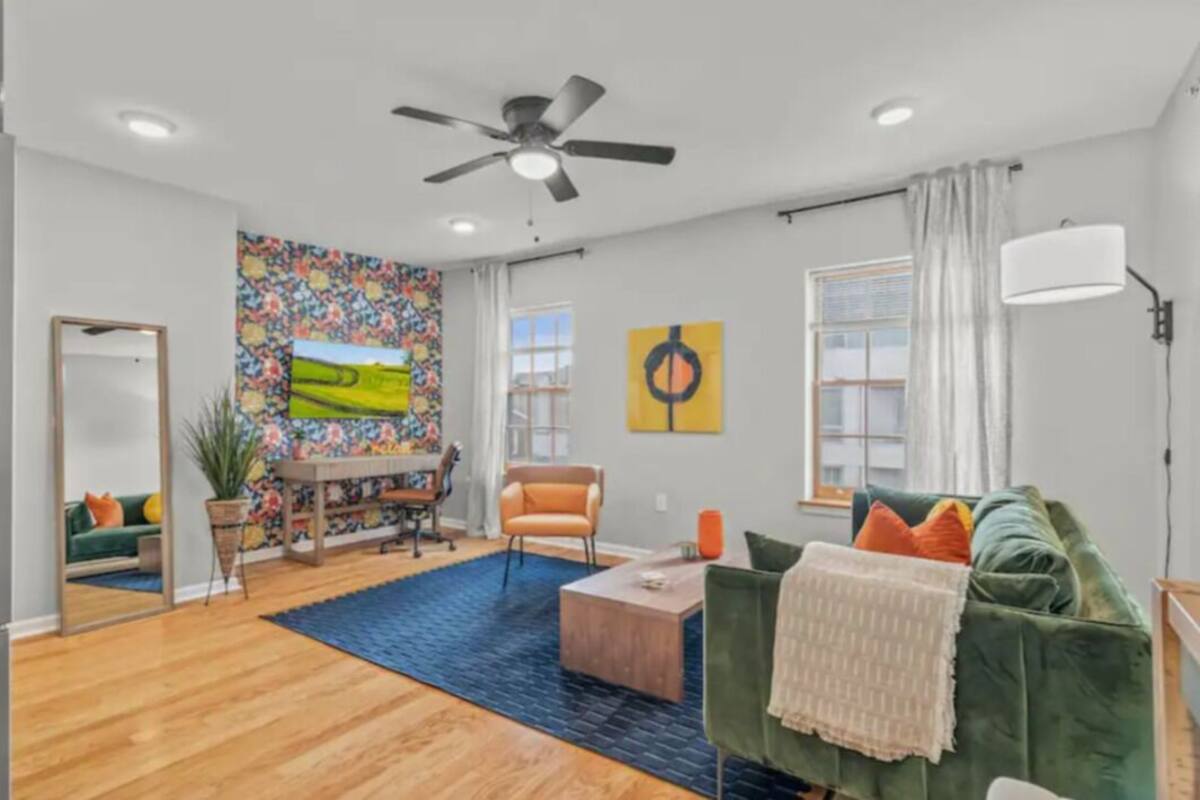 A modern living room with a green sofa, a coffee table, and a colorful abstract painting on the wall.
