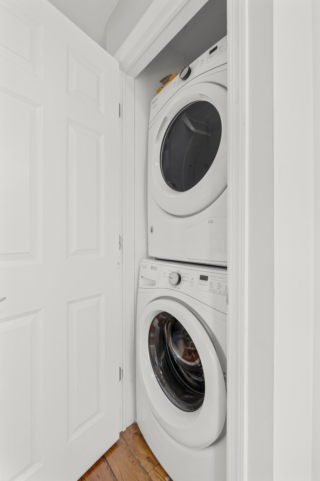 A laundry room with two stacked front-loading washing machines and a white door.
