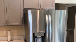 A stainless steel refrigerator with a water dispenser, grey cabinets, and a white countertop. - Pleasant 4-bedroom house in New Roads with WiFi. (New Roads)