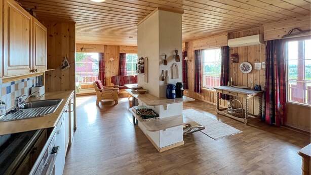 A wooden cabin interior with a kitchen, dining area, and living room.