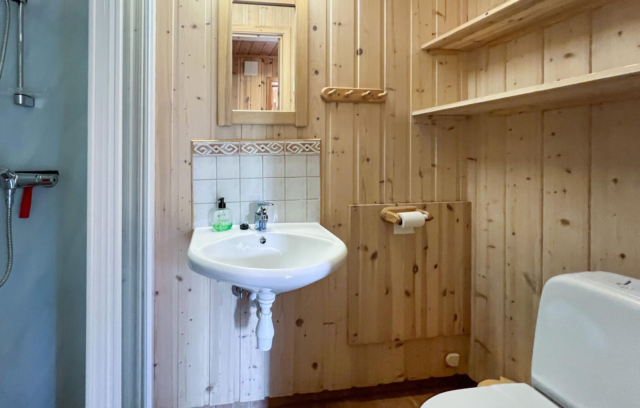 Ein Badezimmer mit einem weißen Waschbecken, einem Spiegel und einer Toilette.