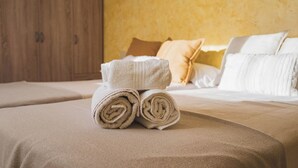 Una cama bien hecha con toallas enrolladas y un armario de madera al fondo.