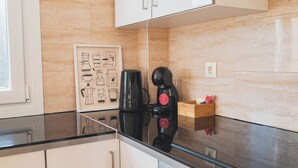 Una cocina con una cafetera, una caja de madera con objetos y una ilustración enmarco de equipo para hacer café.