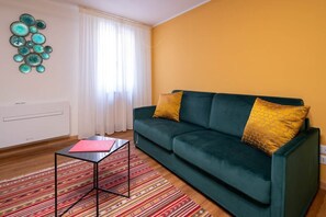 A living room with a green sofa, two yellow cushions, a patterned rug, and a wall art piece. - San Beneto (Venezia)