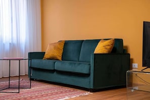 A green sofa with yellow cushions, a small table, and a television on a stand. - San Beneto (Venezia)
