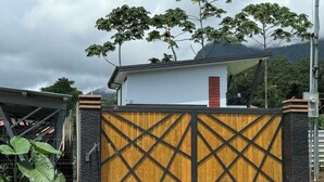 A gated entrance with a wooden gate and a modern house in the background.