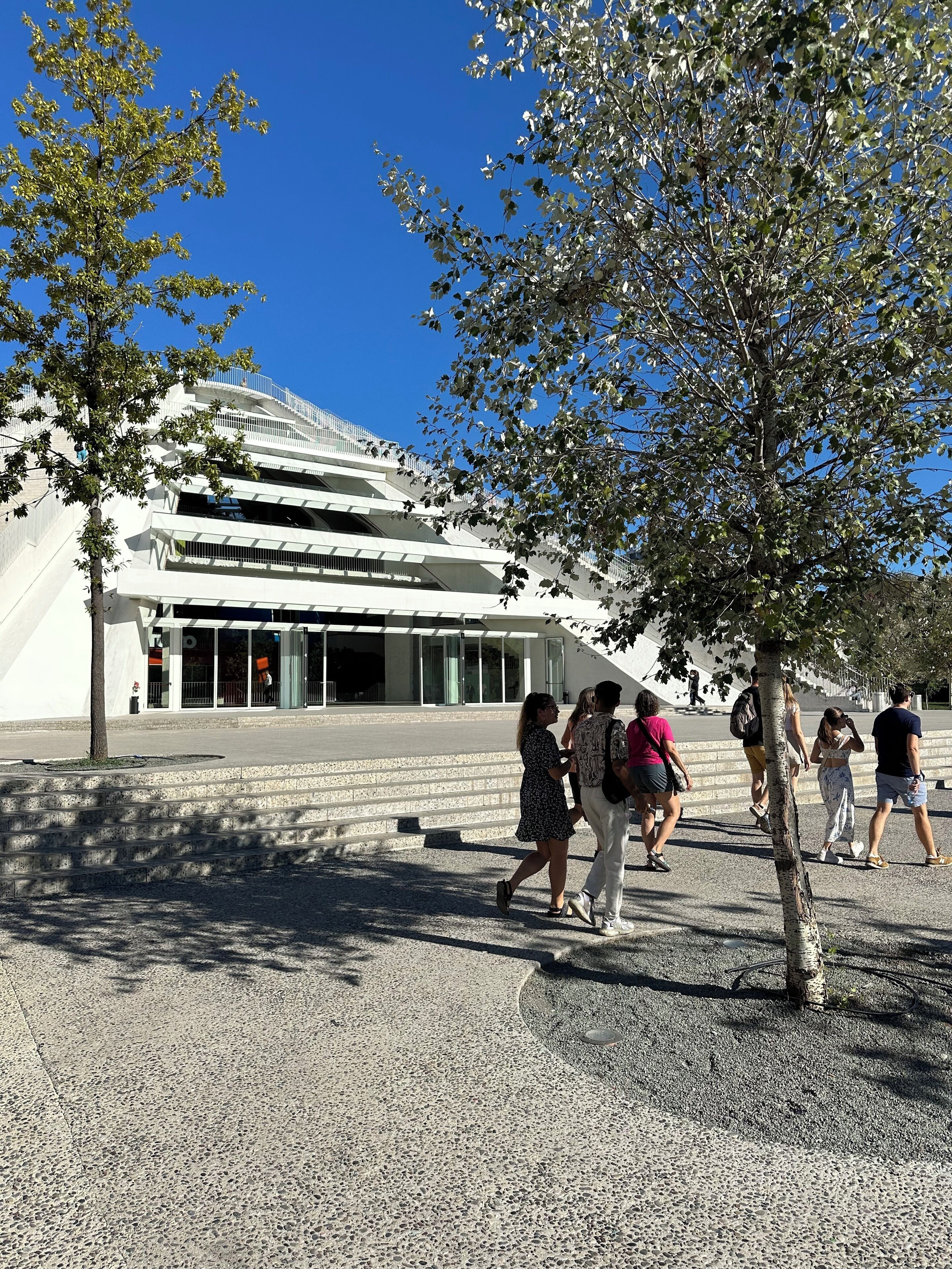 A modern building with a unique architectural design, featuring multiple levels and a prominent entrance.