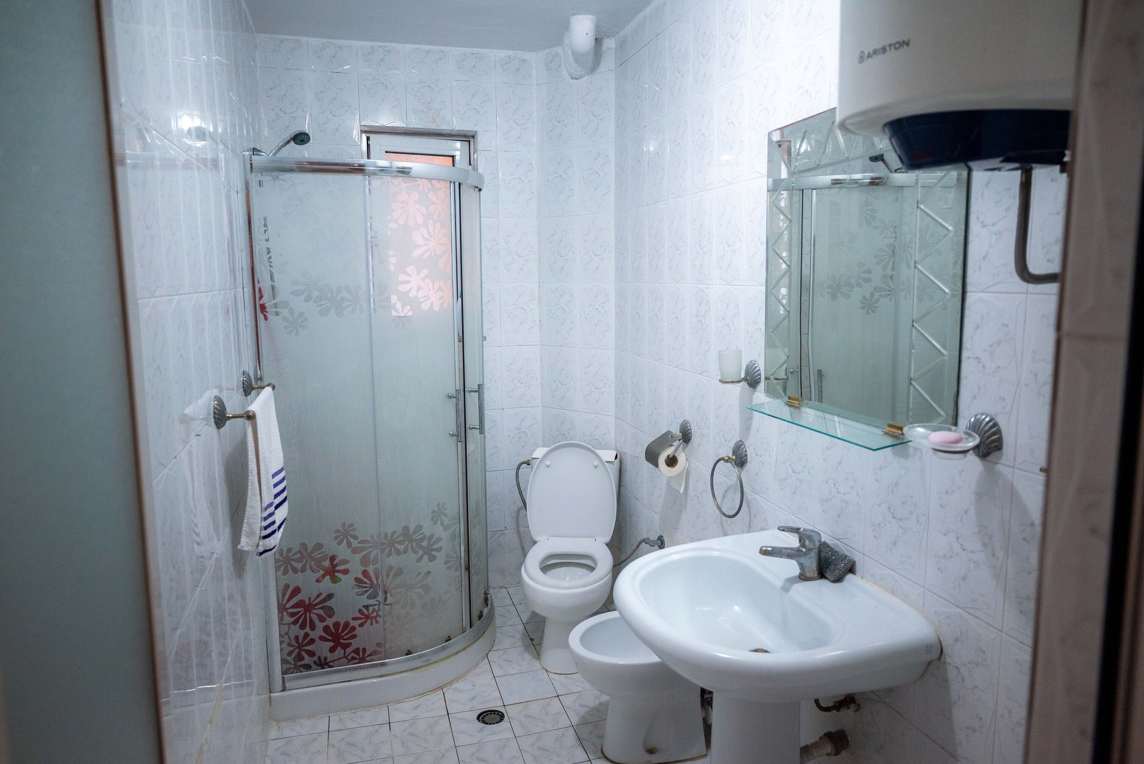 A bathroom with a glass-enclosed shower, a toilet, and a sink.