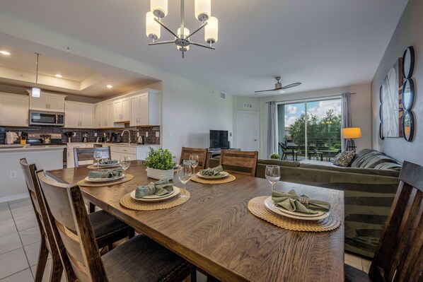 A modern kitchen with white cabinets, a microwave, and a dining area set with wooden chairs and a table.