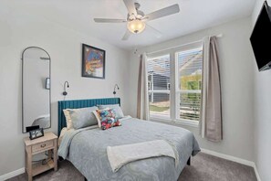Relax in this stylish bedroom with a comfortable bed, large window, and ceiling fan.