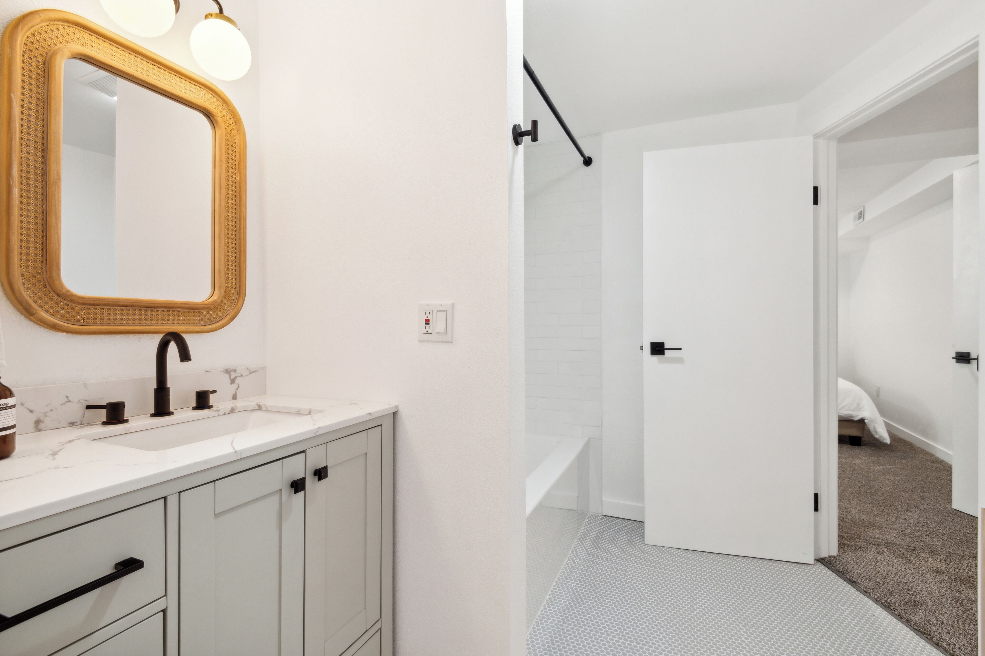 A bathroom with a white vanity, a mirror with a wooden frame, and a shower area with a white door.