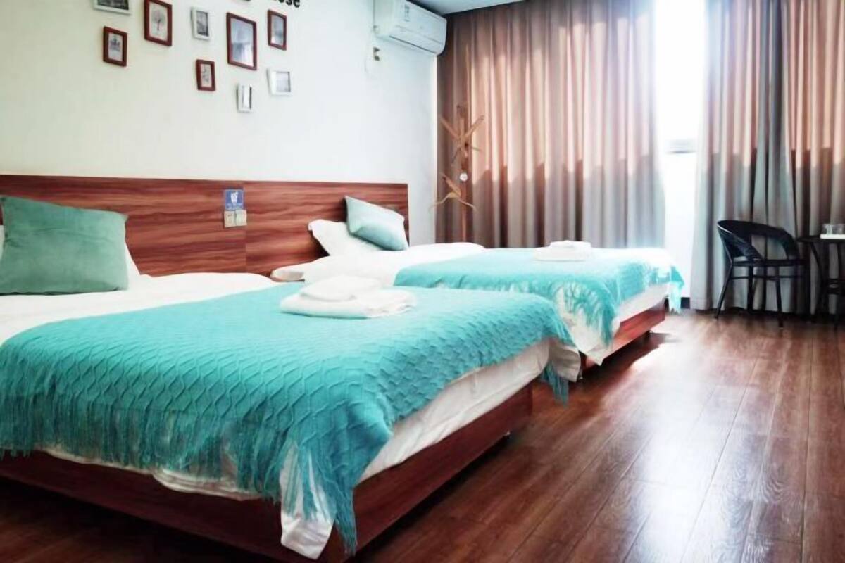 Une chambre d’hôtel avec deux lits, une tête de lit en bois, une petite table et une chaise.