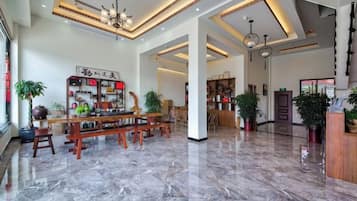 Un vestíbulo amplio con piso de mármol, mobiliario de madera y plantas en macetas.