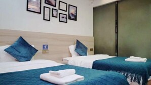 A hotel room with two beds, each with a blue bedspread and white pillows. There are framed pictures on the wall above the beds. - Wuyishan Hike Tea House Inn (Wuyishan)