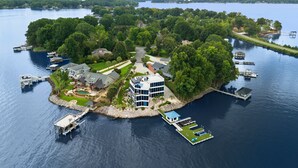 An aerial view of a lakeside property with multiple docks, a central building, and surrounding greenery. - The Glass Mansion w/Optional Boat Rental (Terrell)