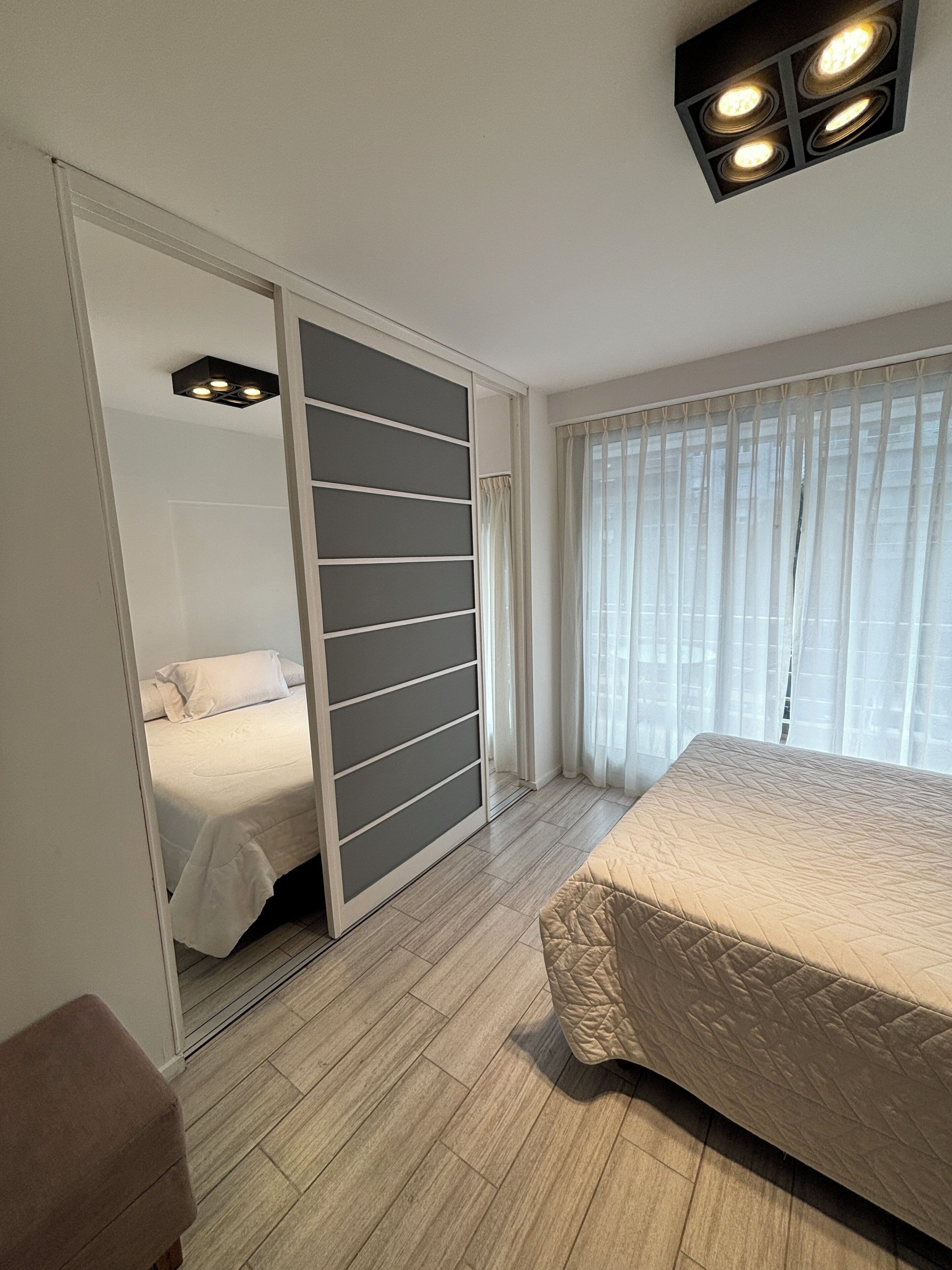 Un dormitorio con cama, armario y ventana con cortinas.