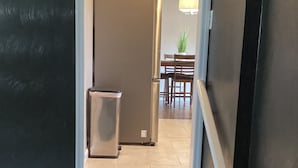 A staircase leading to a dining area with a table and chairs, a refrigerator, and a small cabinet. - Hidden Gem A Comfortable 4bedroom home with a fenced-in yard. (Portsmouth)
