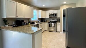 A modern kitchen with white cabinets, a granite countertop, stainless steel appliances, and a wooden floor. - Hidden Gem A Comfortable 4bedroom home with a fenced-in yard. (Portsmouth)