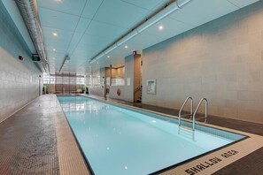 Swimmers can enjoy the pool's shallow area, surrounded by a tiled floor and metal handrails.