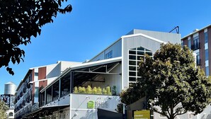 A modern building with a mix of commercial and residential spaces, including a restaurant named "Shake Shack" and various businesses listed on a sign. - Newly Remodel Duplex Free Parking 3-Bed-1 Bath. (Sacramento)