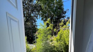 A doorway leading to a wooden deck with a railing, surrounded by greenery and trees. - Newly Remodel Duplex Free Parking 3-Bed-1 Bath. (Sacramento)