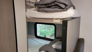 A bunk bed with a window, a pillow, and a blanket. - Cozy RV in charming Pikeville with WiFi, AC (Pikeville)