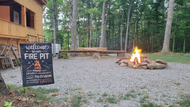 A rustic cabin with a fire pit in the yard surrounded by trees. - Cozy RV in charming Pikeville with WiFi, AC (Pikeville)