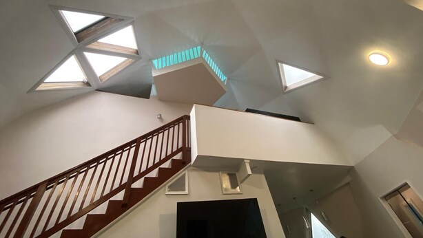Ein mehrgeschossiges Interieur mit Treppe, Oberlichtern und Einbauleuchten.