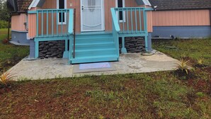 Ein Haus mit einem steilen Satteldach, einer Veranda mit Treppen und einer weißen Tür.