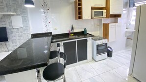 A modern kitchen with a black countertop, white cabinets, a microwave, and a stove.