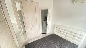 A bedroom with a bed, a wardrobe, and a mirror.