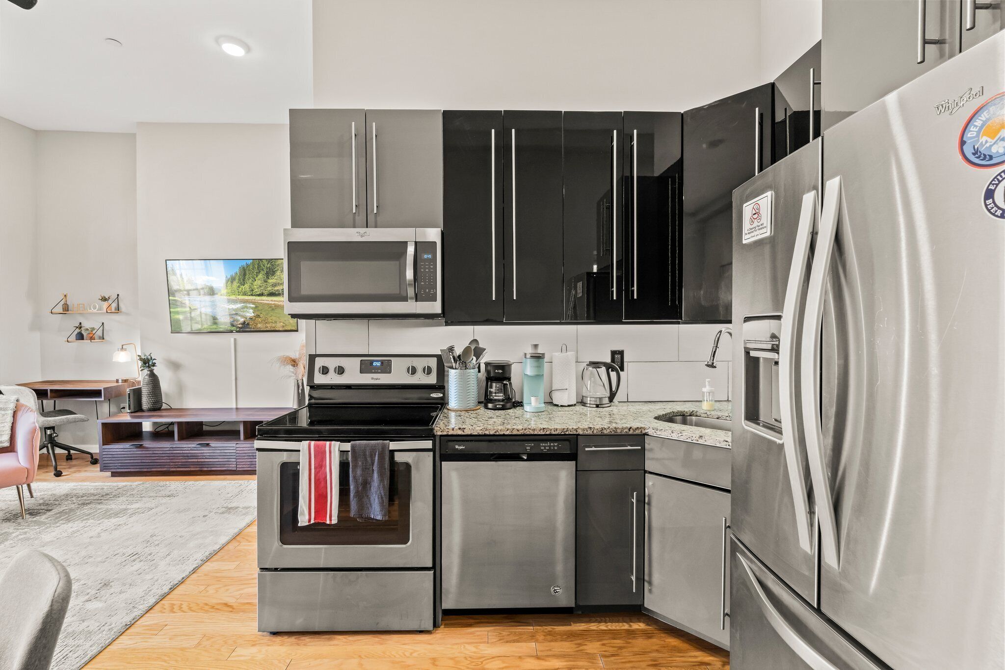A modern kitchen with stainless steel appliances, a microwave, oven, dishwasher, and a refrigerator.