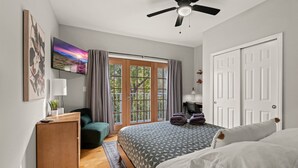 A bedroom with a bed, a desk, a chair, a TV, and a door. - 261 S 17th Street (Philadelphia)